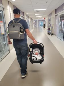 Father leaving the hospital carrying his new baby in a car seat