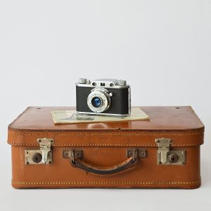 Brown leather suitcase lying down with camera on top