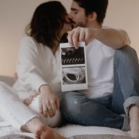 couple sitting down kissing holding a scan picture in the foreground