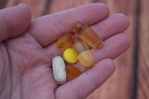 Person's hand holding a range of vitamins and pills