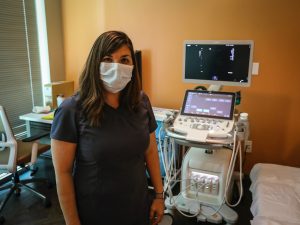 Sonographer in room with ultrasound machine behind her
